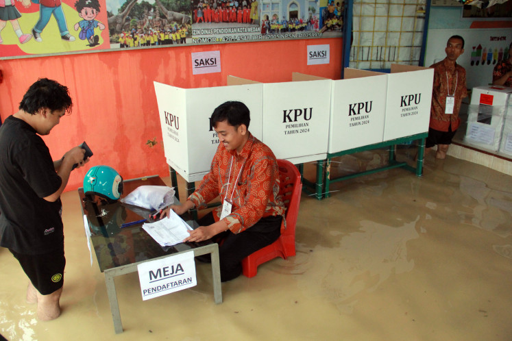 Petugas KPPS membantu seorang pemilih di TPS 9, kecamatan Tanjung Gusta, Medan, Sumatera Utara, hari Rabu, 27 November 2024. Komisi Pemilihan Umum (KPU) kota tersebut menyatakan bahwa 45 TPS harus menjadwalkan ulang hari pemilihan karena banjir.